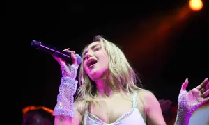 Ana Mena canta en Zaragoza, con un micrófono en la mano y guantes brillantes.