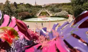 Flores vibrantes en primer plano, con el parque grande Zaragoza florece al fondo, destacando una fuente y senderos verdes.