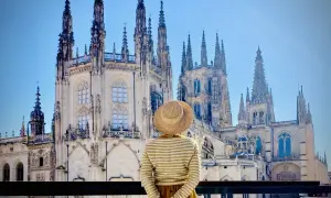 Una persona con sombrero admira la majestuosa Catedral de Burgos, considerada por muchos la mejor catedral de España, con sus imponentes agujas y detalles góticos.