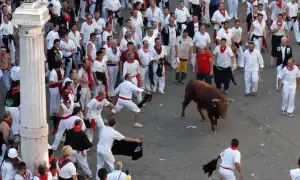 Multitud en el programa fiestas Teruel, con un toro bravo y gente vestida de blanco y rojo.