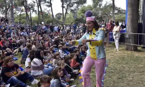 Actriz con traje colorido anima a niños en un espectáculo de marionetas en el parque.