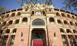 La imponente fachada de la plaza de toros de Zaragoza, con sus arcos y balcones, se alza bajo un cielo azul.