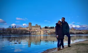 Pareja disfruta de la vista del río Duero y la ciudad de Zamora, un lugar que merece la pena visitar. Patos nadan en el agua azul.