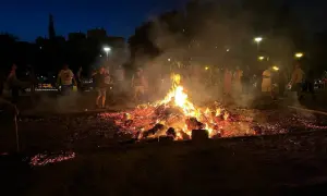 Gente reunida alrededor de una gran hoguera en Zaragoza, celebrando las hogueras de San Juan.