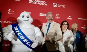 Bibendum, el muñeco Michelin, sonríe junto a autoridades en un evento que celebra la gastronomía de Huesca, destacando la **estrella Michelin Huesca**.