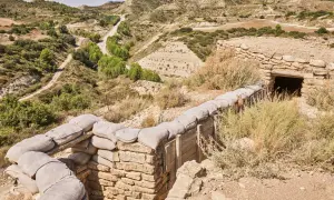 Trincheras de la ruta Orwell, con sacos de arena y un refugio de piedra en un paisaje árido y montañoso.