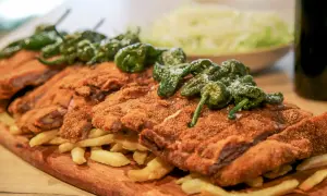 Un festín de cachopo crujiente, patatas fritas doradas y pimientos de Padrón. ¡Una delicia para compartir!