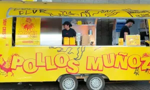 Camión amarillo "Pollos Muñoz" con un gallo rojo. Dos empleados trabajan en el interior.