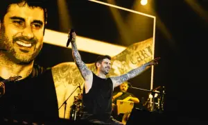 Melendi en concierto en Zaragoza, con los brazos en alto y sonriendo, ante una multitud.