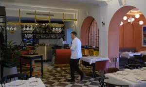 Interior de restaurantes arrabal Zaragoza. Mesas puestas, barra con botellas y un chef camina.