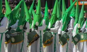 Nazarenos con túnicas blancas y capirotes verdes desfilan en la ruta cofrade Zaragoza, tambores resonando.