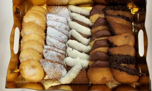 Bandeja dorada con surtido de galletas: almendradas, espolvoreadas con azúcar glas, bañadas en chocolate blanco y negro. ¡La mejor pastelería Zaragoza!