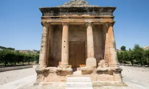 El mausoleo de Fabara, con sus columnas y puerta de madera, se alza imponente bajo un cielo azul.