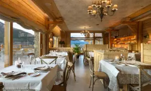 Elegante comedor de madera con mesas puestas, vistas a la montaña. Un lugar perfecto para disfrutar de los restaurantes del Valle de Tena.