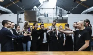 Equipo brindando con copas de vino en una cocina profesional, celebrando el éxito culinario que podría llevar a estrellas Michelin Zaragoza.
