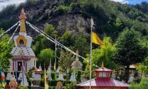 El templo budista Huesca, rodeado de vegetación, con estupas blancas y banderas de oración ondeando.
