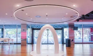 Un arco blanco futurista en el centro del espacio Xplora Ibercaja, con una iluminación circular en el techo y grandes ventanales al exterior.