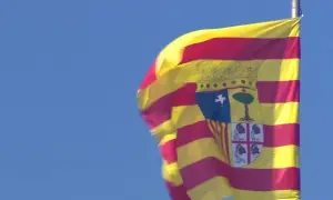 Bandera de San Jorge de Aragón ondeando con orgullo contra el cielo azul.