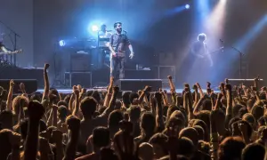 Una banda en vivo toca para una multitud eufórica. Los **fiz horarios** de la música llenan el aire mientras los fans levantan los puños.