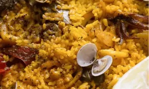 Deliciosa paella en Zaragoza, con arroz amarillo, mejillones, calamares y un toque de limón.