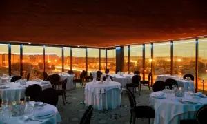 Elegante comedor con mesas puestas y vistas panorámicas de Zaragoza al atardecer. Un lugar perfecto para una cena especial en el rooftop.