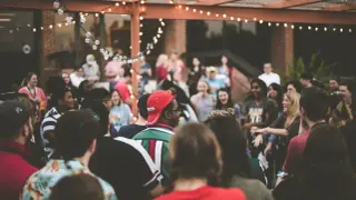 Gente reunida bajo luces, disfrutando de un ambiente festivo. Parece que están celebrando **que es el tardeo**, un momento perfecto para socializar y divertirse.