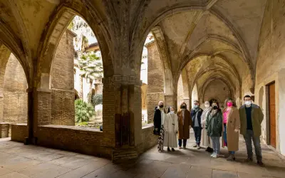 Un grupo visita el claustro del monasterio de la Resurrección en Zaragoza, admirando su arquitectura y vegetación.