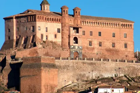 Imponente castillo de ladrillo rojo, con torres y cúpulas, coronando una colina. Un lugar perfecto para imaginar el festival de los castillos.