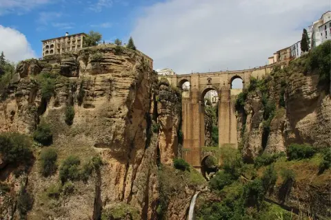 Impresionante puente de piedra sobre un profundo desfiladero, uno de los puentes de España más icónicos. Edificios en lo alto de los acantilados.