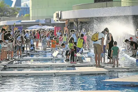 Niños y adultos disfrutan de un **espacio río y juego** con actividades acuáticas bajo el sol.