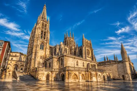 La majestuosa catedral de Burgos se alza bajo un cielo azul con nubes algodonosas.