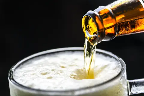 Cerveza dorada cayendo de una botella a un vaso espumoso. ¡Una birra Zaragoza perfecta para refrescarse!