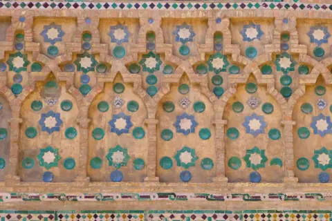 Detalle de azulejos de la Seo Zaragoza, con estrellas de ocho puntas en azul y verde sobre fondo de ladrillo y detalles circulares.