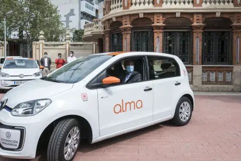 Un hombre con mascarilla conduce un coche blanco de carsharing en Zaragoza.