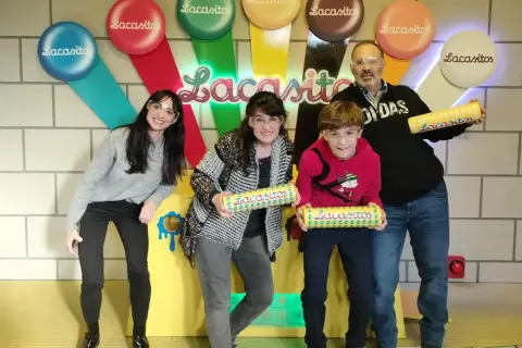 Familia sonriente posa con tubos de Lacasitos en un escape room temático. ¡Una aventura dulce y divertida!