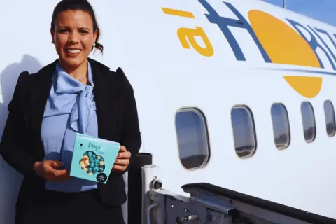 Mujer sonriente con caja de palomitas junto a un avión con el logo "air horizont".