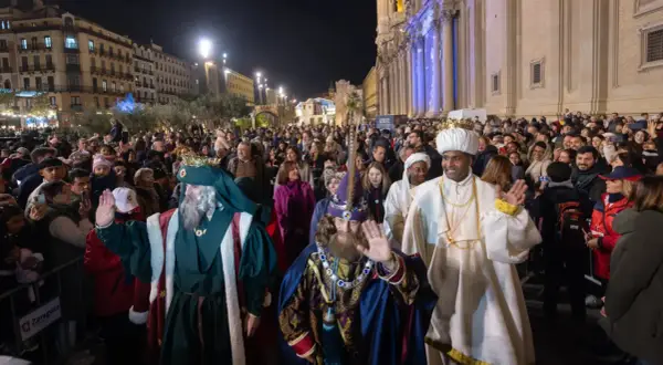 La cabalgata Miralbueno ilumina la noche con los Reyes Magos saludando a la multitud.
