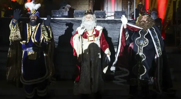 Los Reyes Magos saludan al público en la cabalgata de Reyes de Huesca, con sus trajes brillantes y coronas.