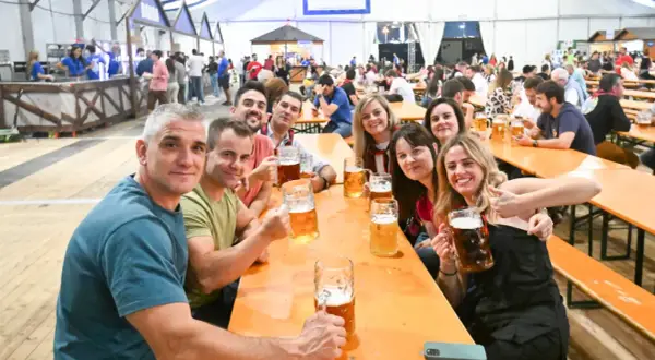 Amigos brindando con jarras de cerveza en el oktober valdespartera. Ambiente festivo y sonrisas.