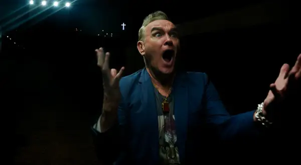 Morrissey en Zaragoza, con gesto dramático y las manos alzadas, bajo luces y una cruz.