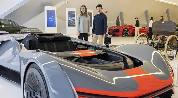 Jóvenes observan coches futuristas y clásicos en una exposición de coches en Zaragoza.