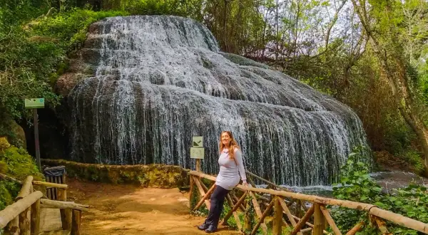 Cascada espectacular, ideal para descubrir qué ver cerca de Calatayud. Una mujer sonríe apoyada en una barandilla de madera.