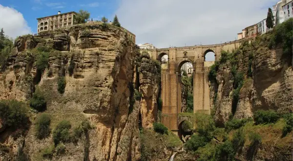 Impresionante puente de piedra sobre un profundo desfiladero, uno de los puentes de España más icónicos. Edificios en lo alto de los acantilados.