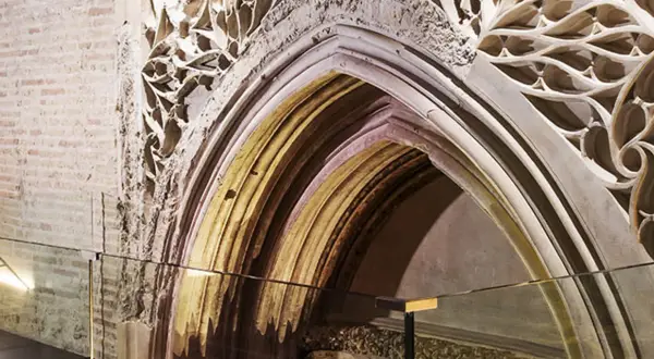 Detalle arquitectónico de un arco gótico en el museo Alma Mater, con ladrillo expuesto y ornamentación de piedra calada.