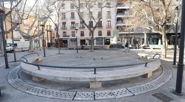 Banqueta circular de piedra en la plaza San Pedro Nolasco Zaragoza, con árboles desnudos y edificios al fondo.