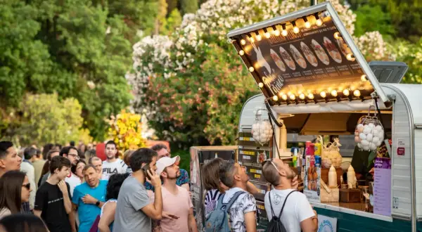 Gente disfrutando en un programa food truck Zaragoza, con un camión de comida iluminado y lleno de gente esperando.