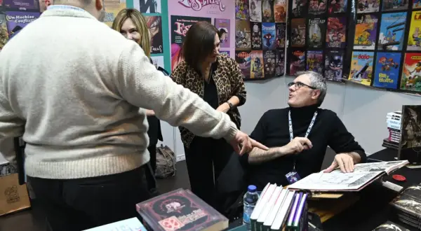 En la Comic Con Zaragoza, un autor firma cómics mientras fans observan.