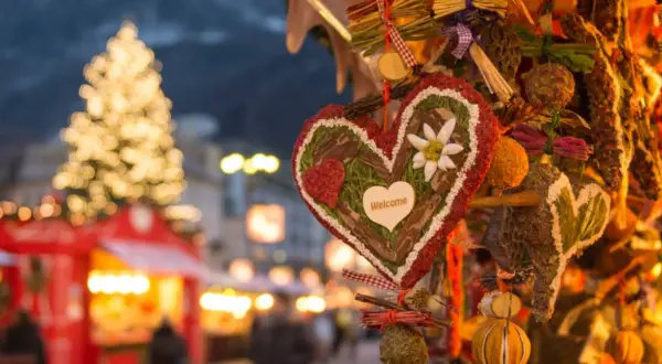 Corazón decorado con "Welcome" en un mercadillo navideño de Calatayud. Luces de árbol y puestos de feria al fondo.