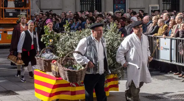 Hombres con trajes tradicionales desfilan en las fiestas Cuarte de Huerva, portando cestas con uvas y pan.