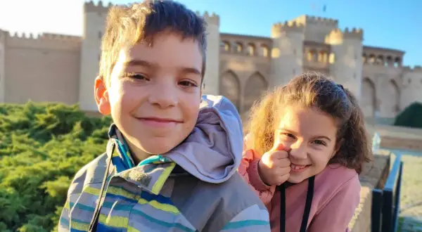 Dos niños sonríen frente a un palacio en Zaragoza. ¡Una aventura familiar en el museo!